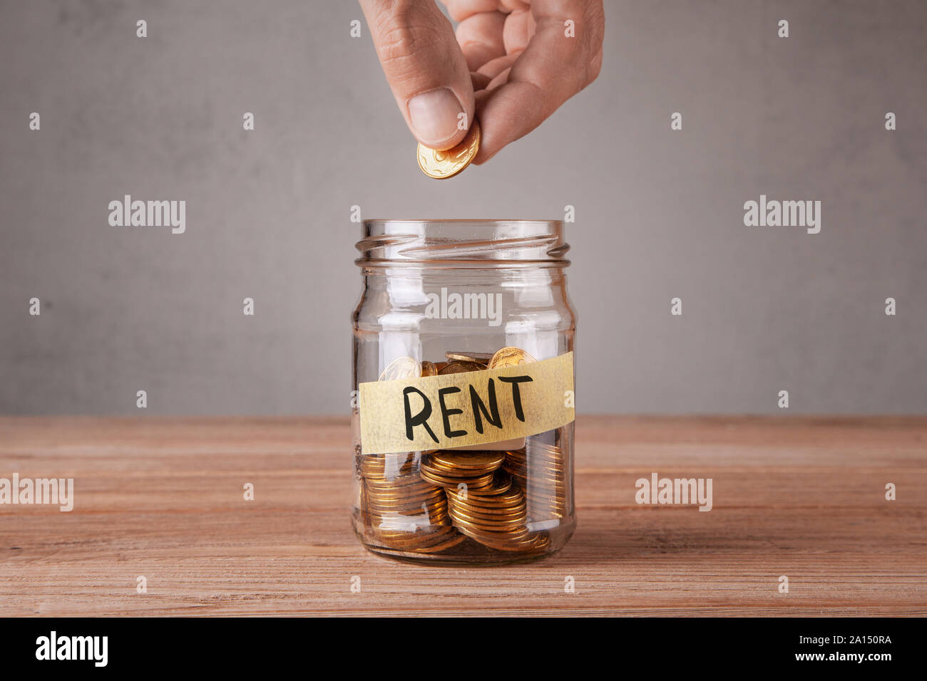 Louer. Bocal en verre avec des pièces de monnaie et une inscription louer. Pièce de l'homme tient dans sa main Banque D'Images