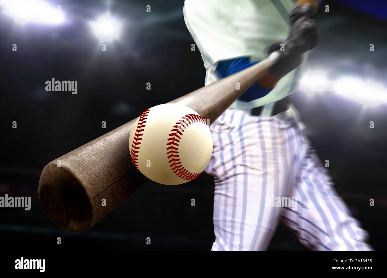 Baseball player hitting ball avec bat in close up sous les projecteurs du stade Banque D'Images