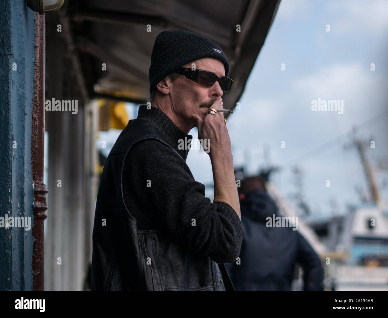 Un homme dans un Beanie Hat fumer une cigarette sur la rue Banque D'Images