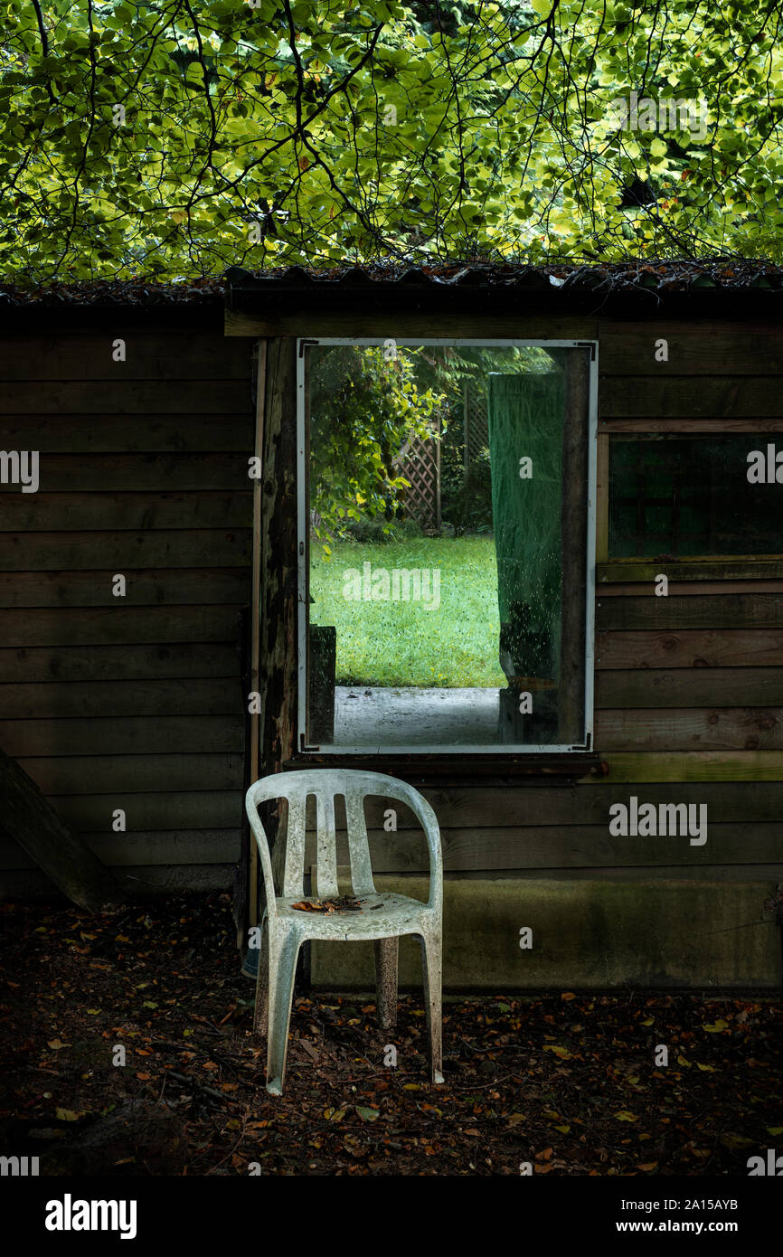 Chaise en plastique derrière un abri de jardin. Banque D'Images