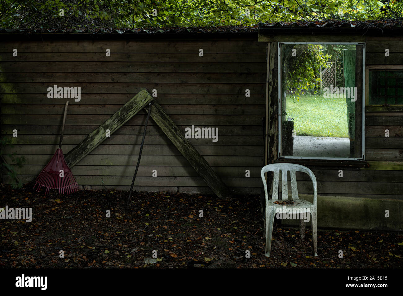 Chaise en plastique derrière un abri de jardin. Banque D'Images