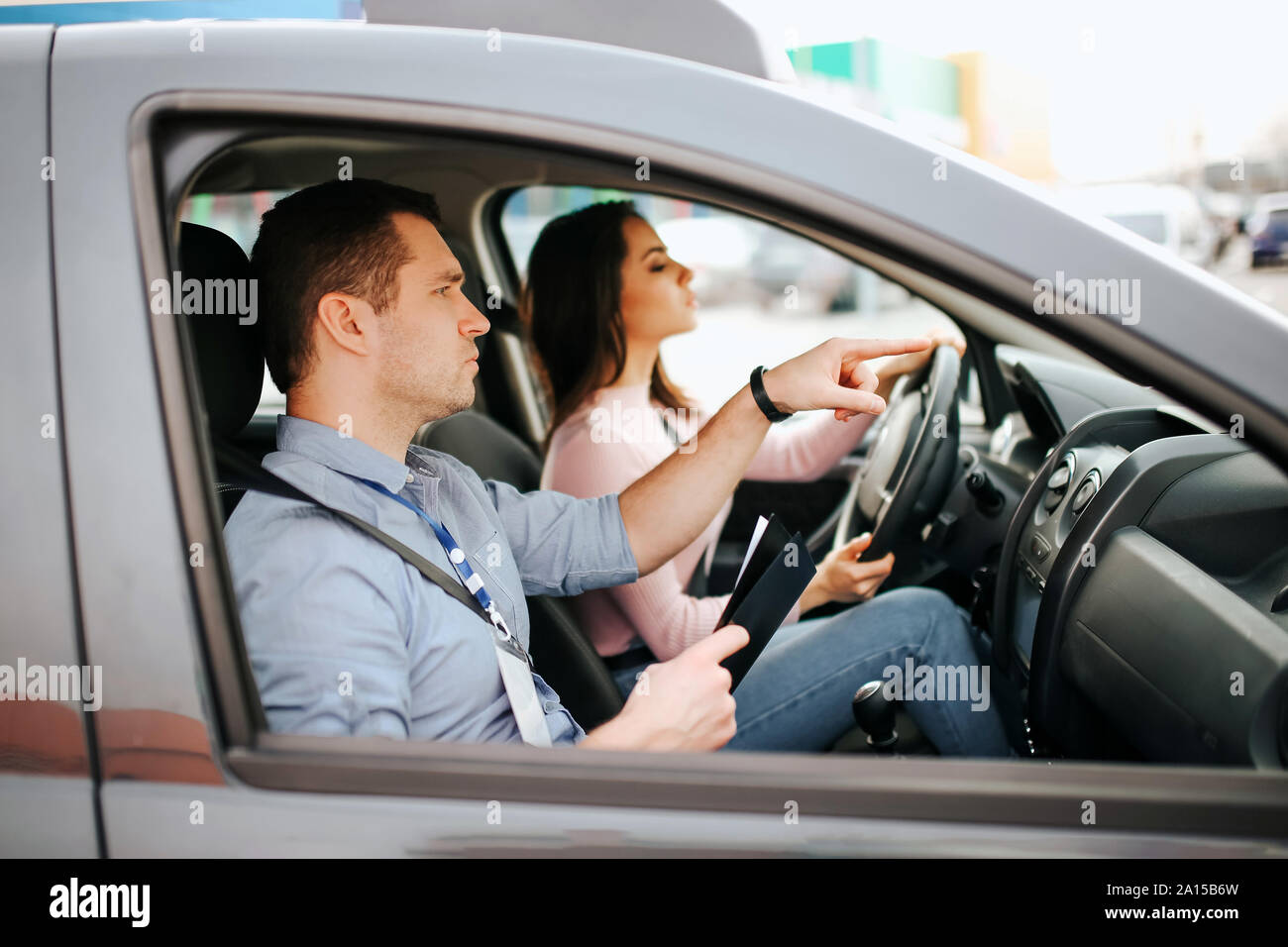 Auto mâle formateur prend l examen en jeune femme. Conduite prudente et en passant un examen pratique. Avec l'aide de l'instructeur de conduite. Jeune femme passage test avec c Banque D'Images