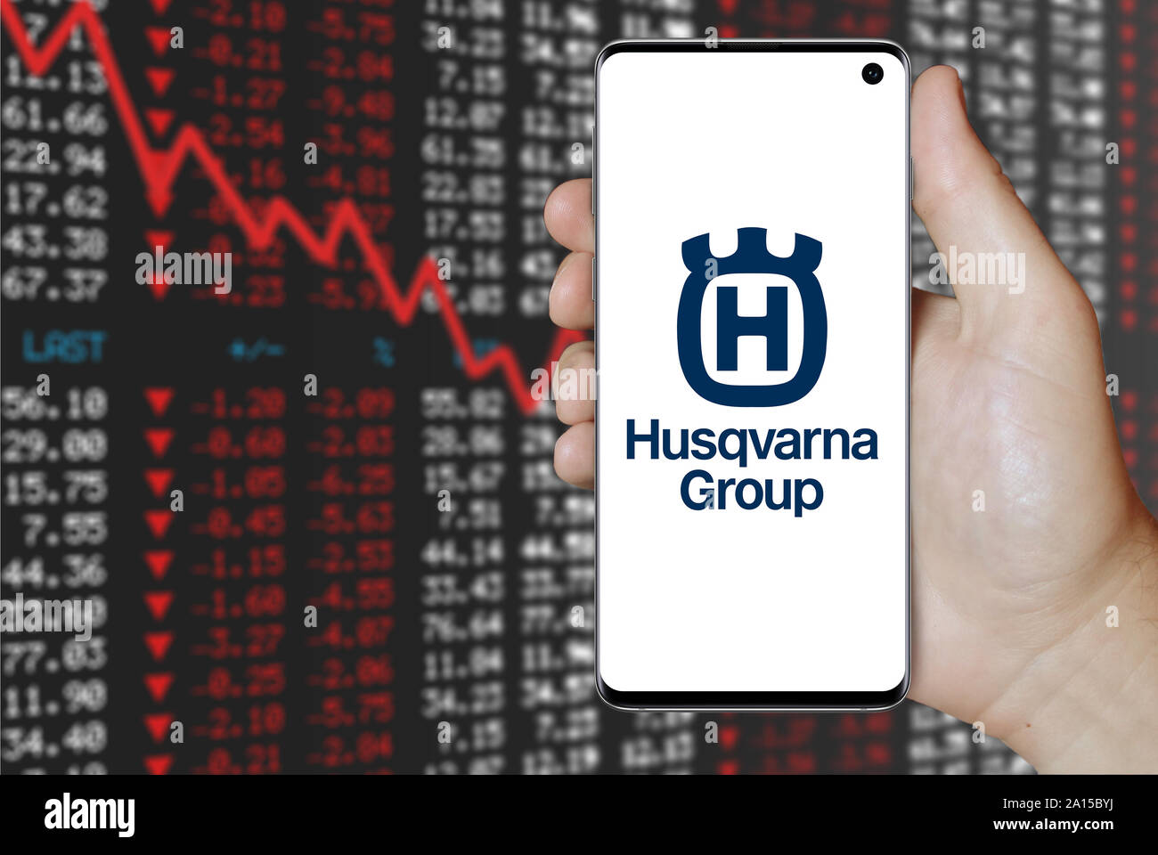 Un homme est titulaire d'un smartphone affichant le logo de société Husqvarna énumérés sur OMX Stockholm. Contexte du marché boursier négatif. Credit : PIXDUCE Banque D'Images