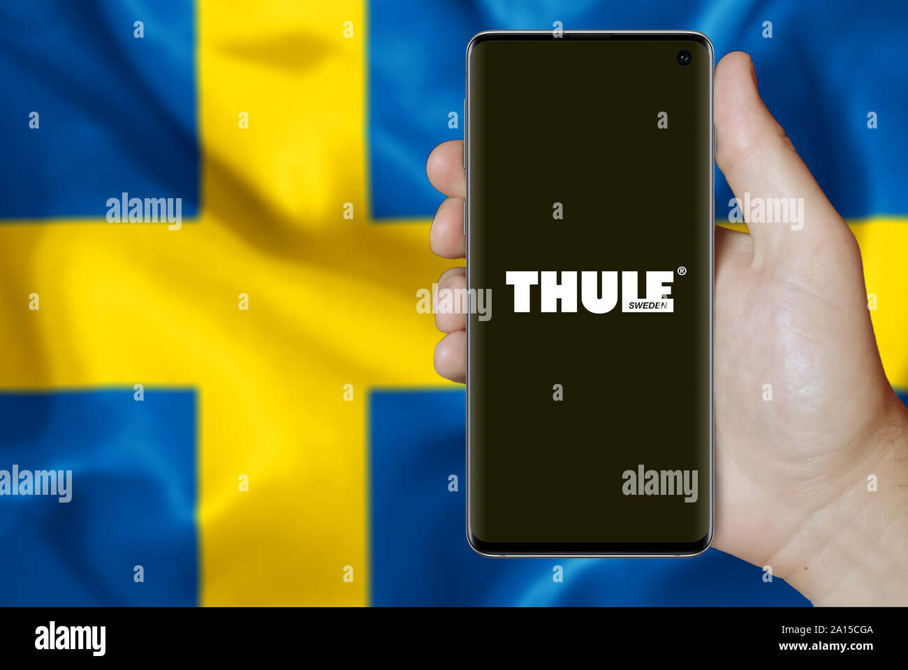 Un homme est titulaire d'un smartphone affichant le logo de société cotée à Thulé OMX Stockholm. Drapeau suédois dans l'arrière-plan. Credit : PIXDUCE Banque D'Images