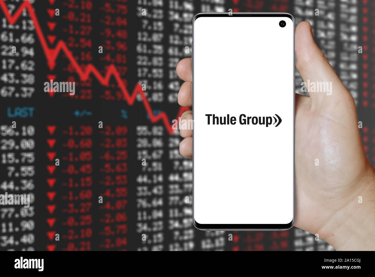 Un homme est titulaire d'un smartphone affichant le logo de société du groupe Thule énumérés sur OMX Stockholm. Contexte du marché boursier négatif. Credit : PIXDUCE Banque D'Images