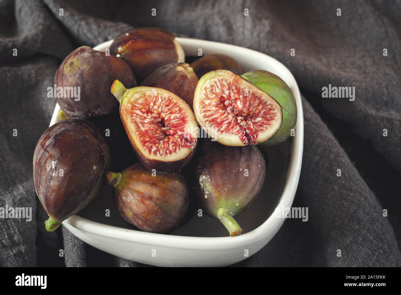 Figues entières et d'une fig coupé en deux sur le dessus d'une table. Banque D'Images