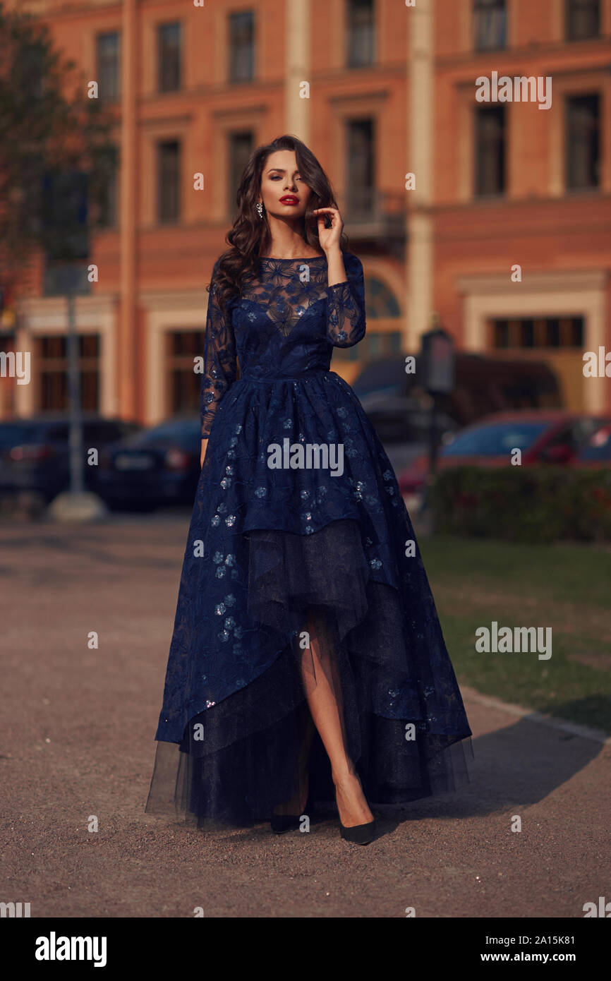 Femme élégante en robe robe de bal bleu et permanent qui pose le long d'une  soirée à la rue. Modèle de mode portrait Photo Stock - Alamy