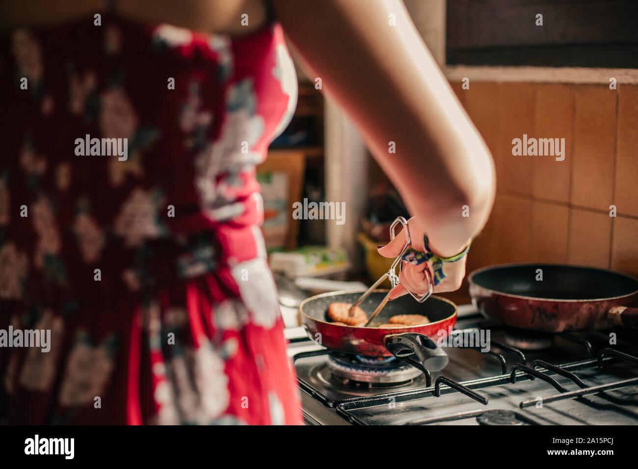 Close-up of woman cooking in kitchen en utilisant une casserole Banque D'Images
