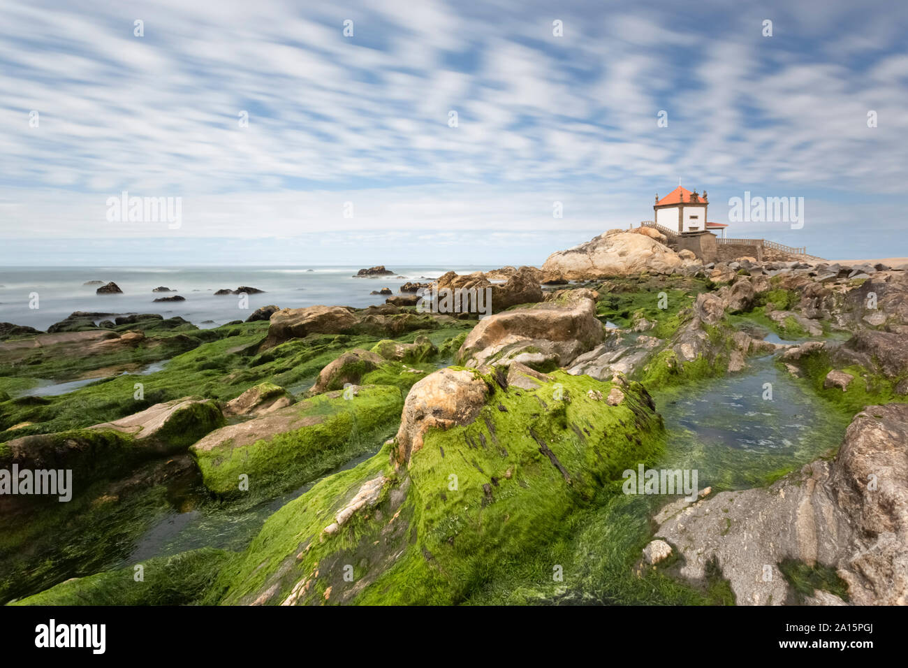 Chapelle de sur Senhor da Pedra rock formation par mer contre ciel nuageux Banque D'Images