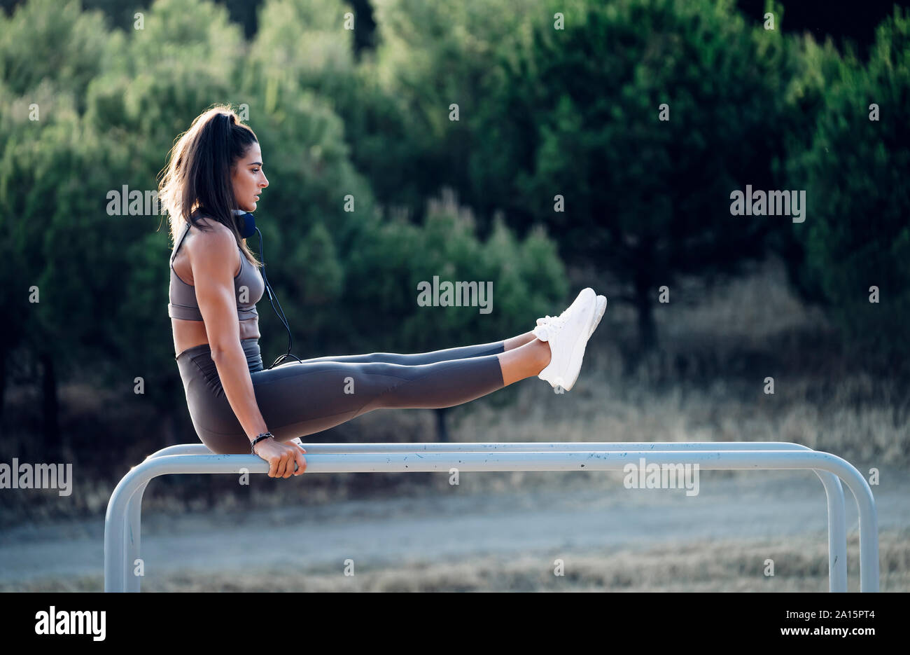 Jeune femme exercsing sur barres parallèles Banque D'Images