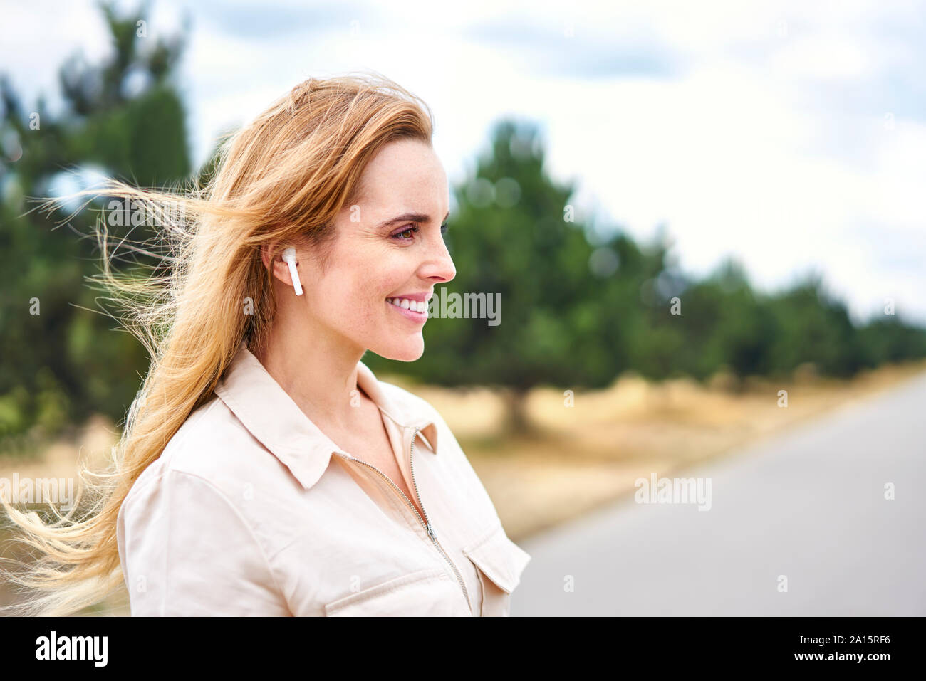 Portrait de femme heureuse avec des écouteurs sans fil dans la nature Banque D'Images Portrait de femme heureuse avec des écouteurs sans fil dans la nature Banque D'Images