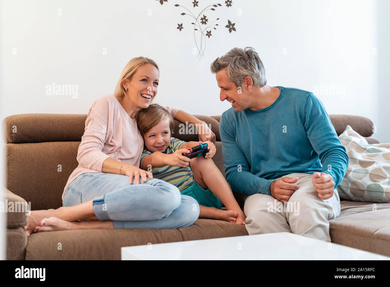 Les parents heureux avec son playing video game sur la table à la maison Banque D'Images Les parents heureux avec son playing video game sur la table à la maison Banque D'Images