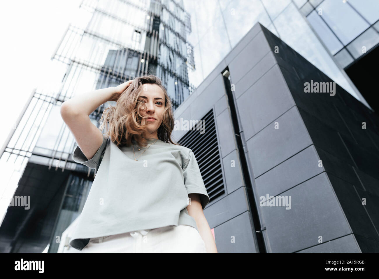 Portrait of smiling woman looking at camera, immeubles de bureaux modernes à l'arrière-plan, low angle view Banque D'Images