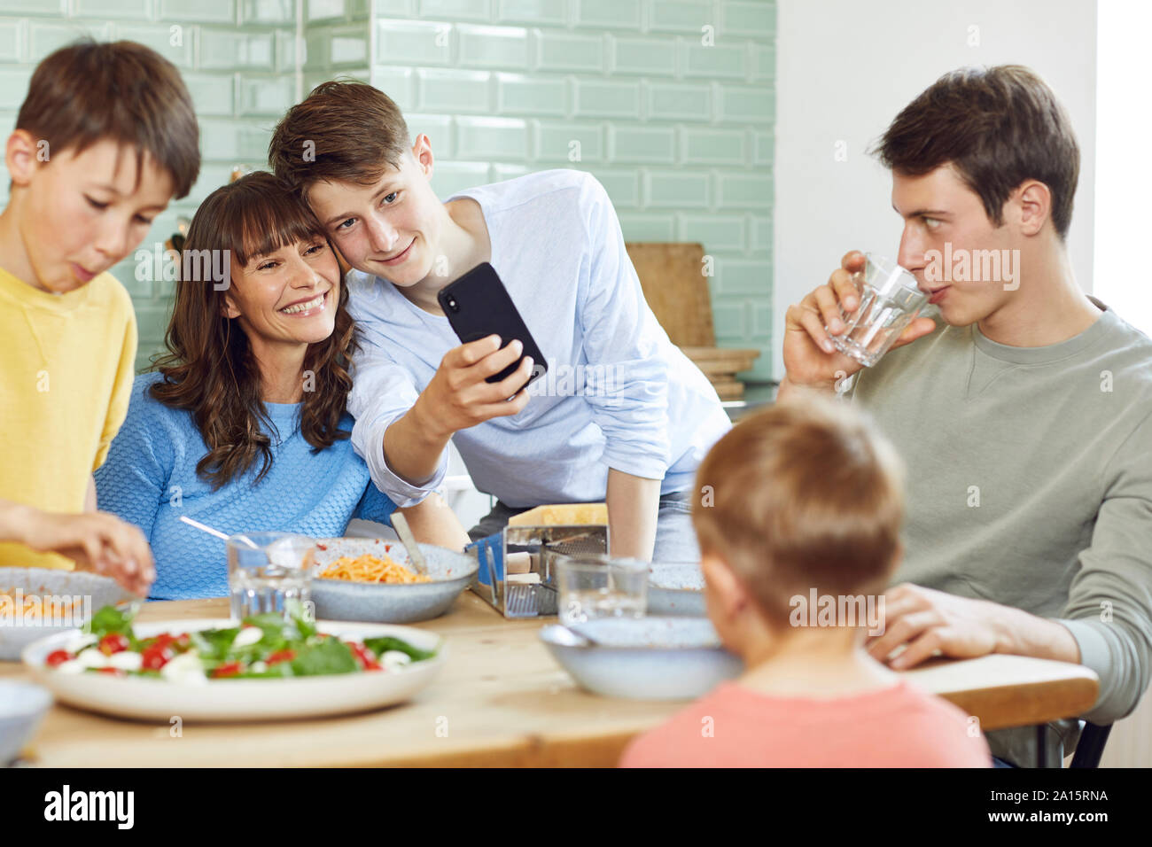 La mère et ses quatre fils en tenant vos autoportraits smartphone au déjeuner Banque D'Images