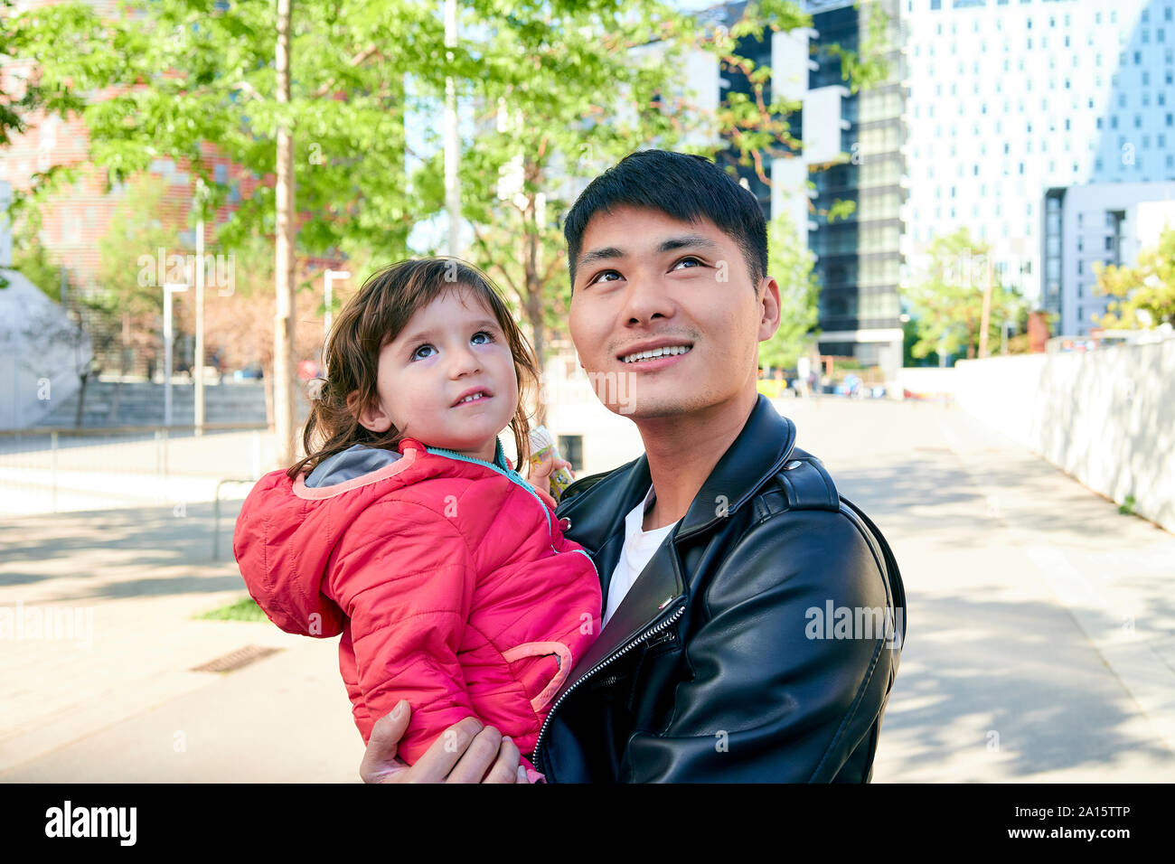 Smiling father holding little daughter looking up Banque D'Images