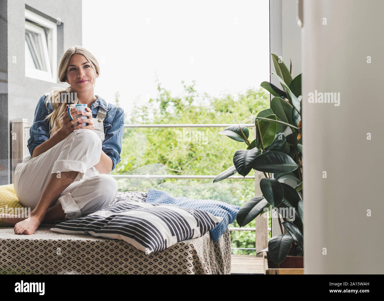 Femme assise à la fenêtre à la maison avoir une pause-café Banque D'Images