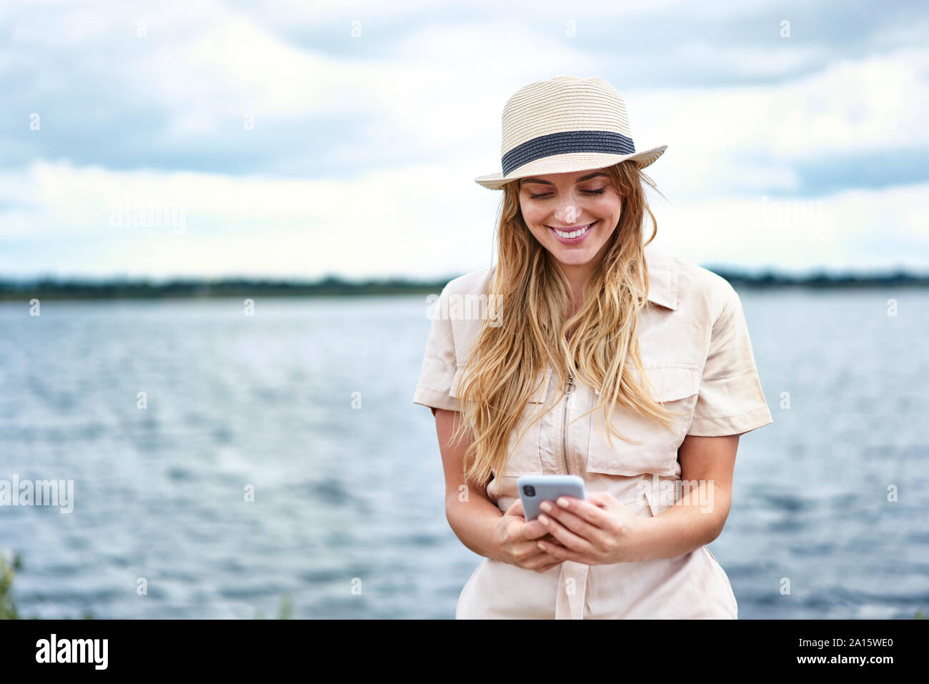 Happy woman checking cell phone au bord de lac Banque D'Images