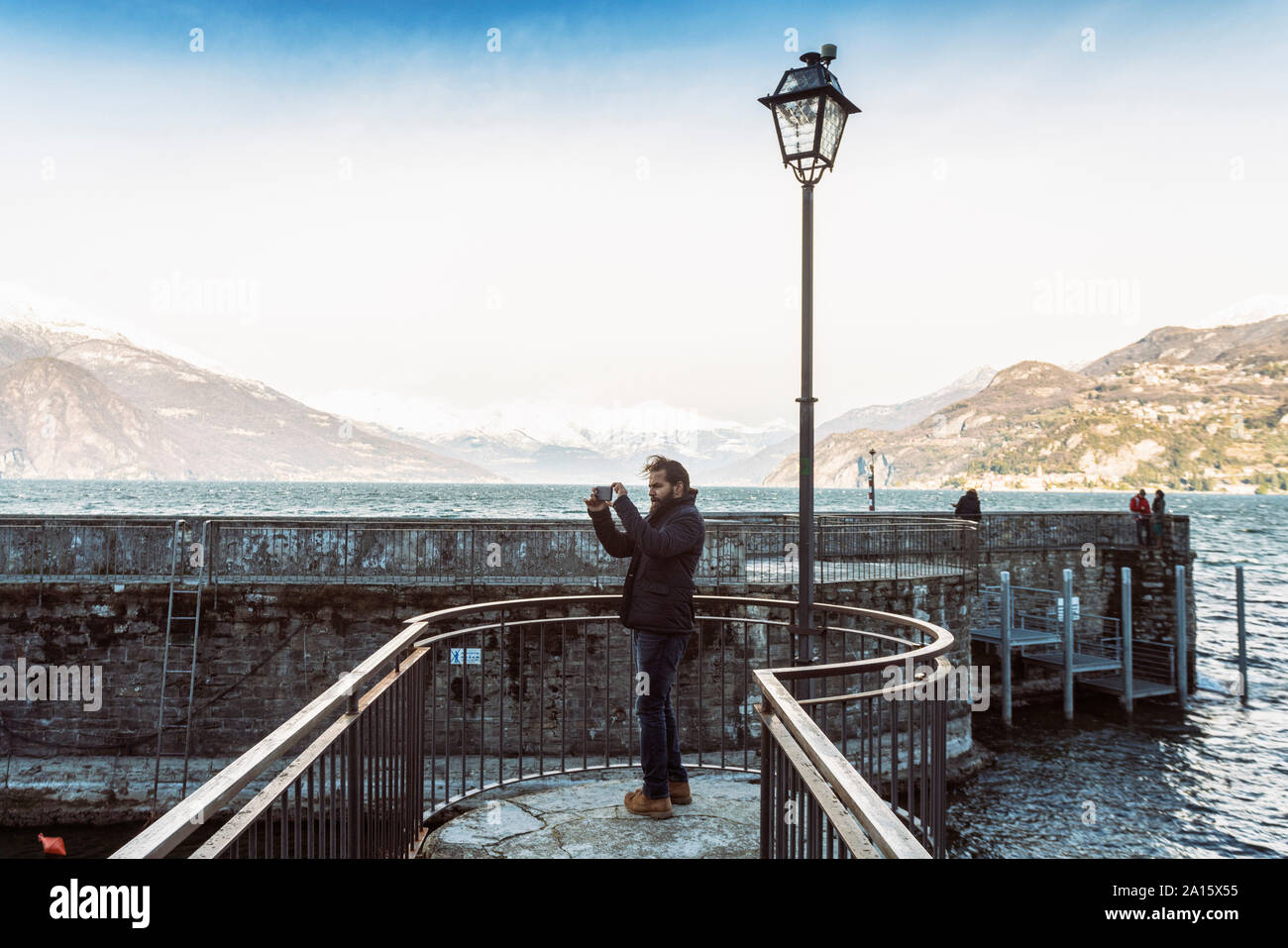 L'homme à l'aide de téléphone mobile de prendre des photos au lac de Côme en hiver, Italie Banque D'Images