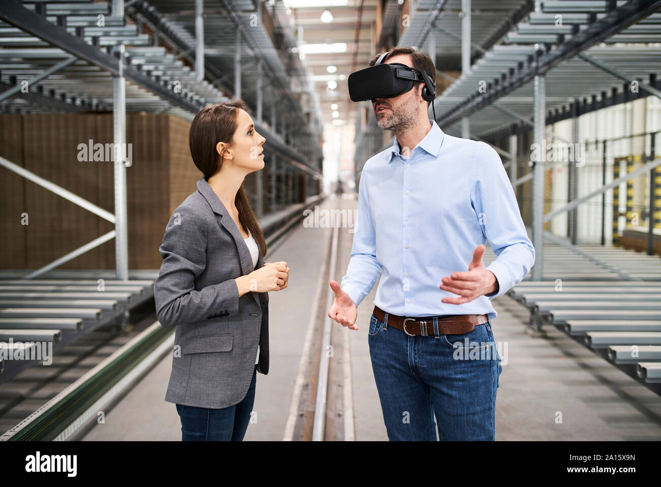 Businesswoman talking to businessman wearing glasses VR en usine Banque D'Images