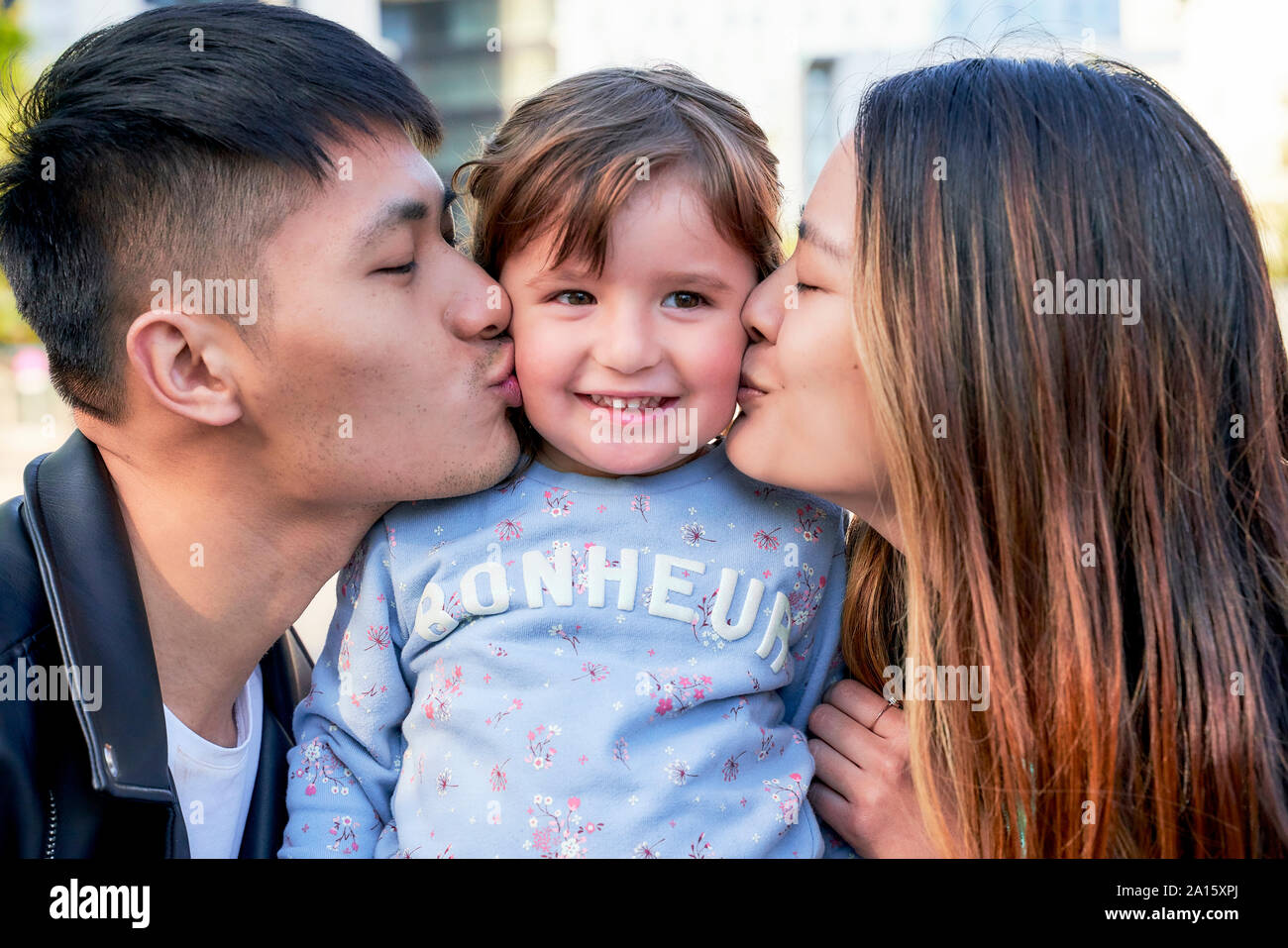 Heureux parents kissing little girl Banque D'Images
