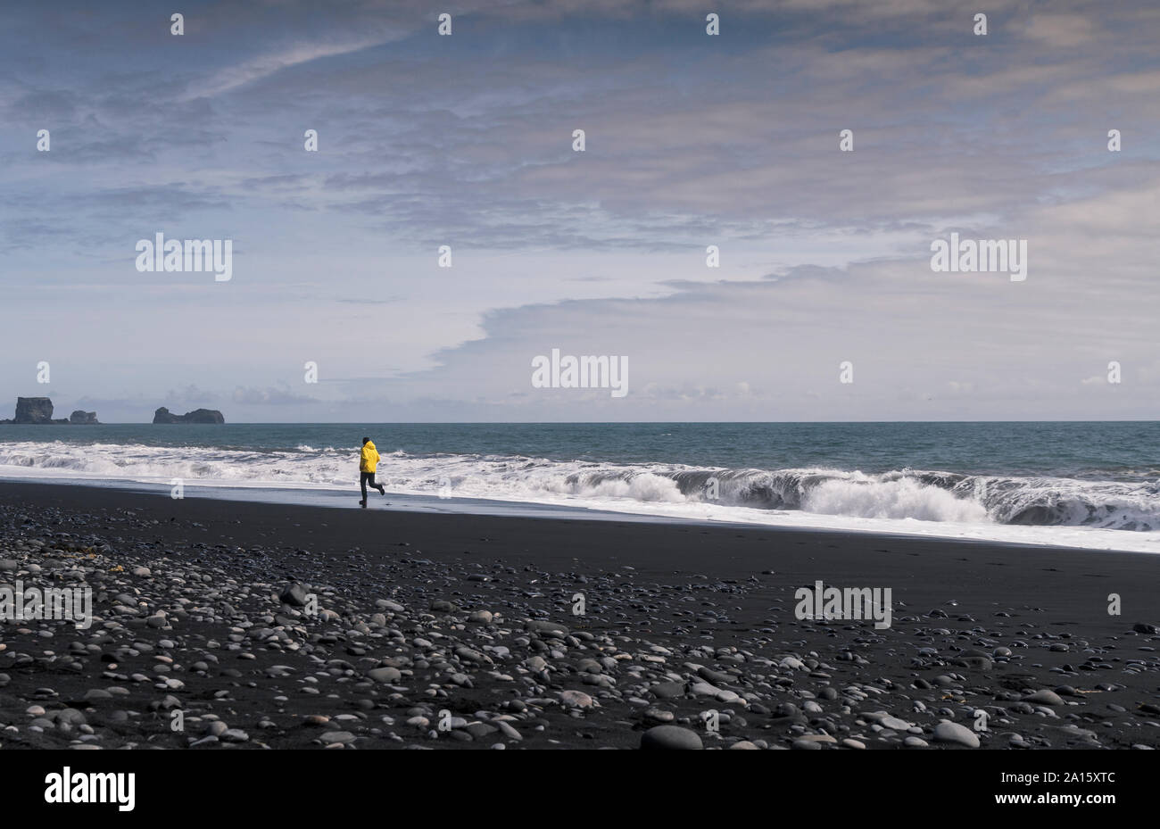 Homme mûr s'exécutant sur une plage de lave en Islande Banque D'Images