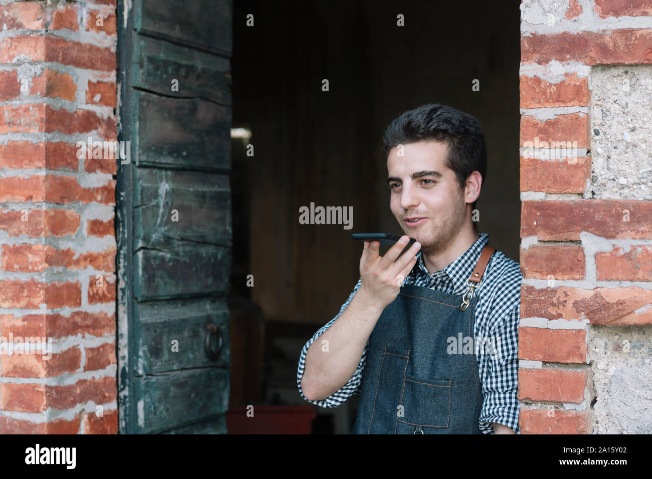 Smiling young farmer using smartphone Banque D'Images