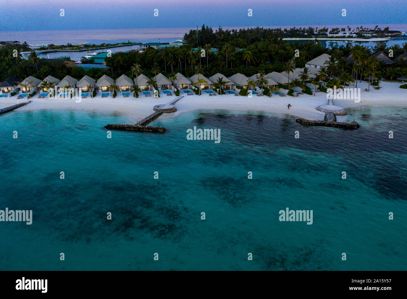 Les Maldives, l'île Olhuveli, Resort et jetées sur South Male Atoll au coucher du soleil Banque D'Images