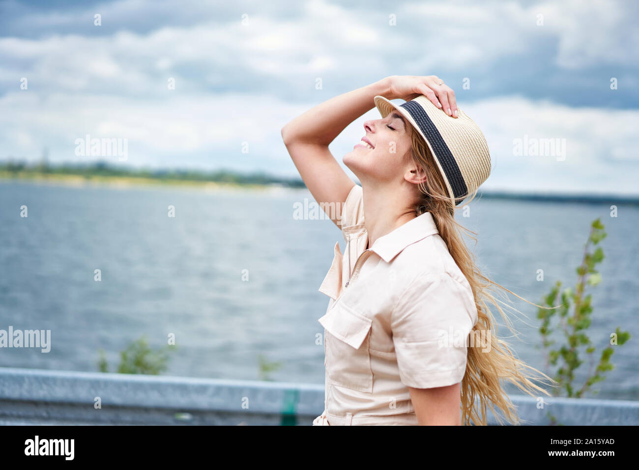 Femme aux yeux clos s'adossant au bord de lac Banque D'Images
