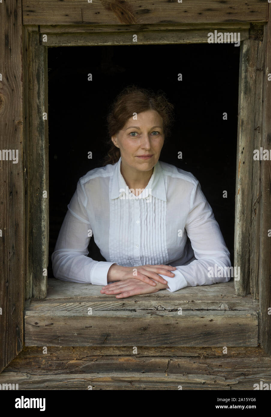 Portrait de femme à la fenêtre de d'une vieille maison en bois Banque D'Images