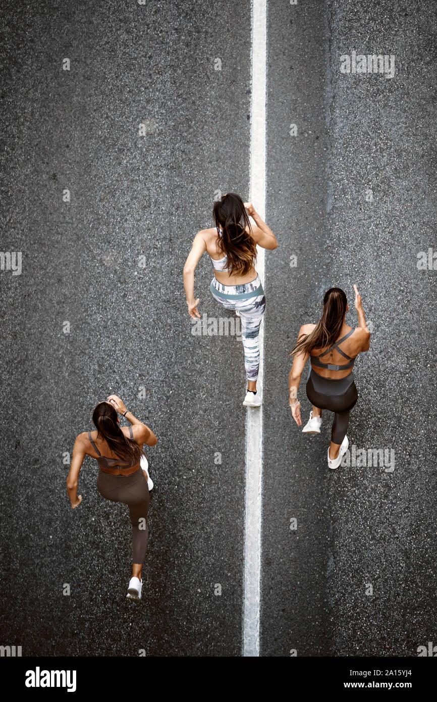 Vue du haut de trois jeunes femmes sportive s'exécutant sur une rue Banque D'Images