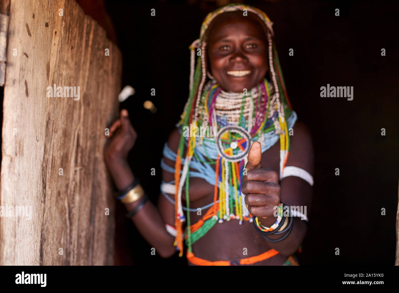 Portrait d'une femme traditionnelle Muhila debout dans sa maison, donnant, humbs Congolo, Angola Banque D'Images