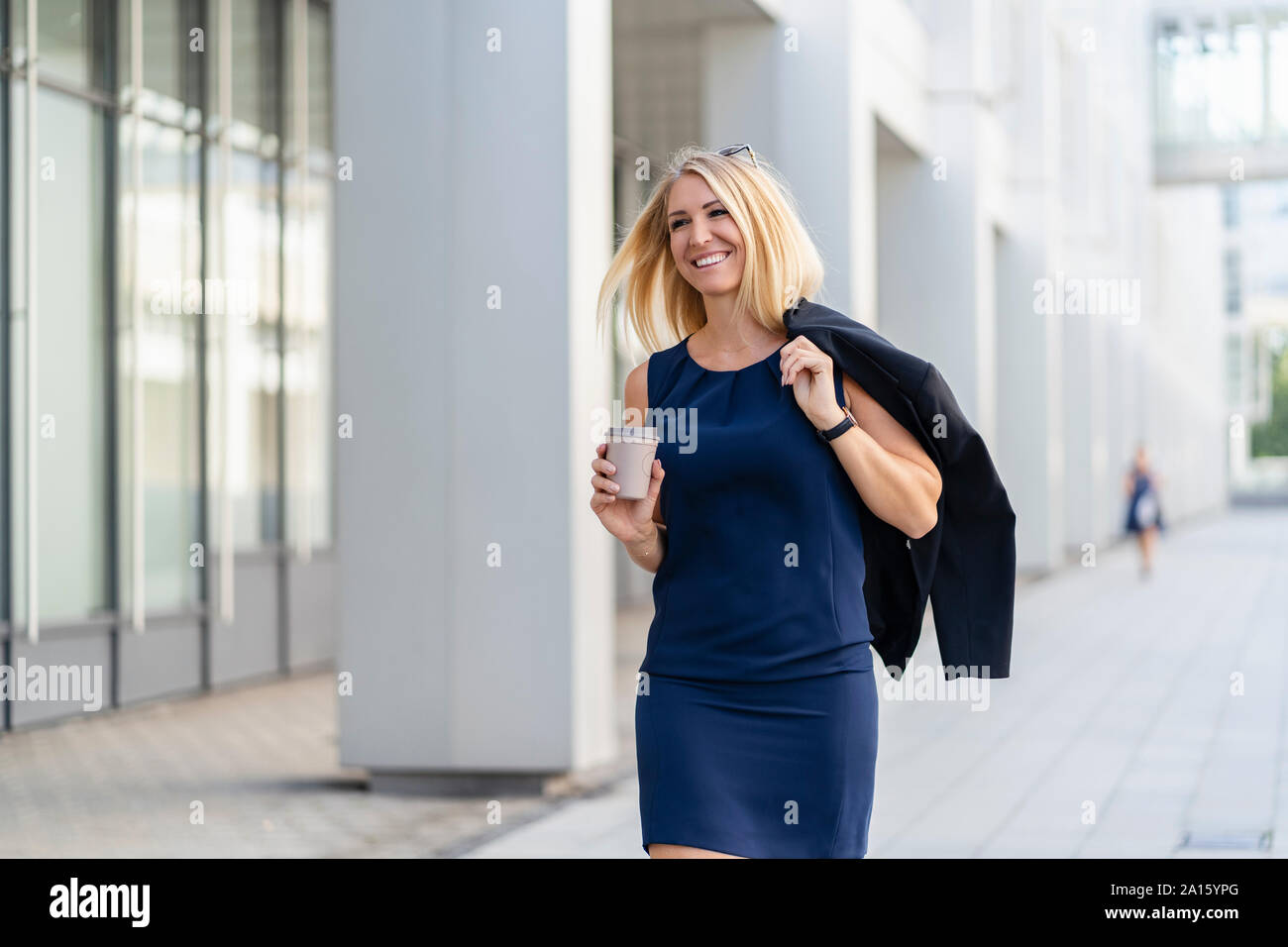 Portrait of smiling blonde businesswoman with coffee pour aller porter robe d'été bleu Banque D'Images