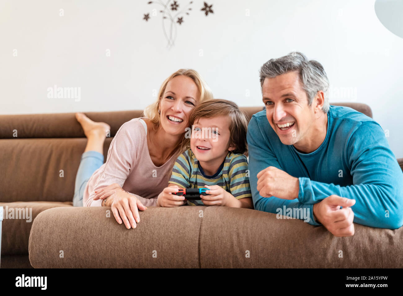 Les parents heureux avec son playing video game sur la table à la maison Banque D'Images Les parents heureux avec son playing video game sur la table à la maison Banque D'Images