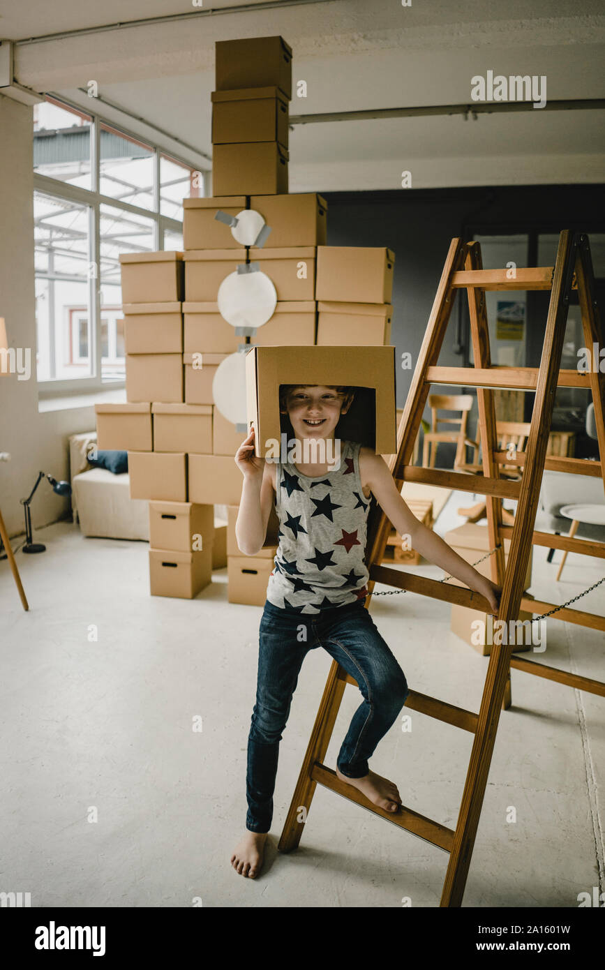Portrait de l'astronaute Garçon jouant rousse debout devant rocket construit de boîtes de carton Banque D'Images