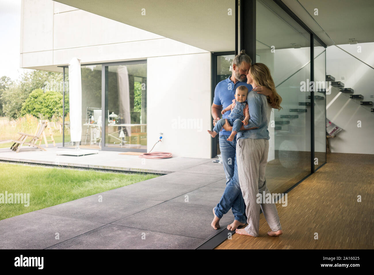 Famille de trois personnes debout à la fenêtre à la maison Banque D'Images