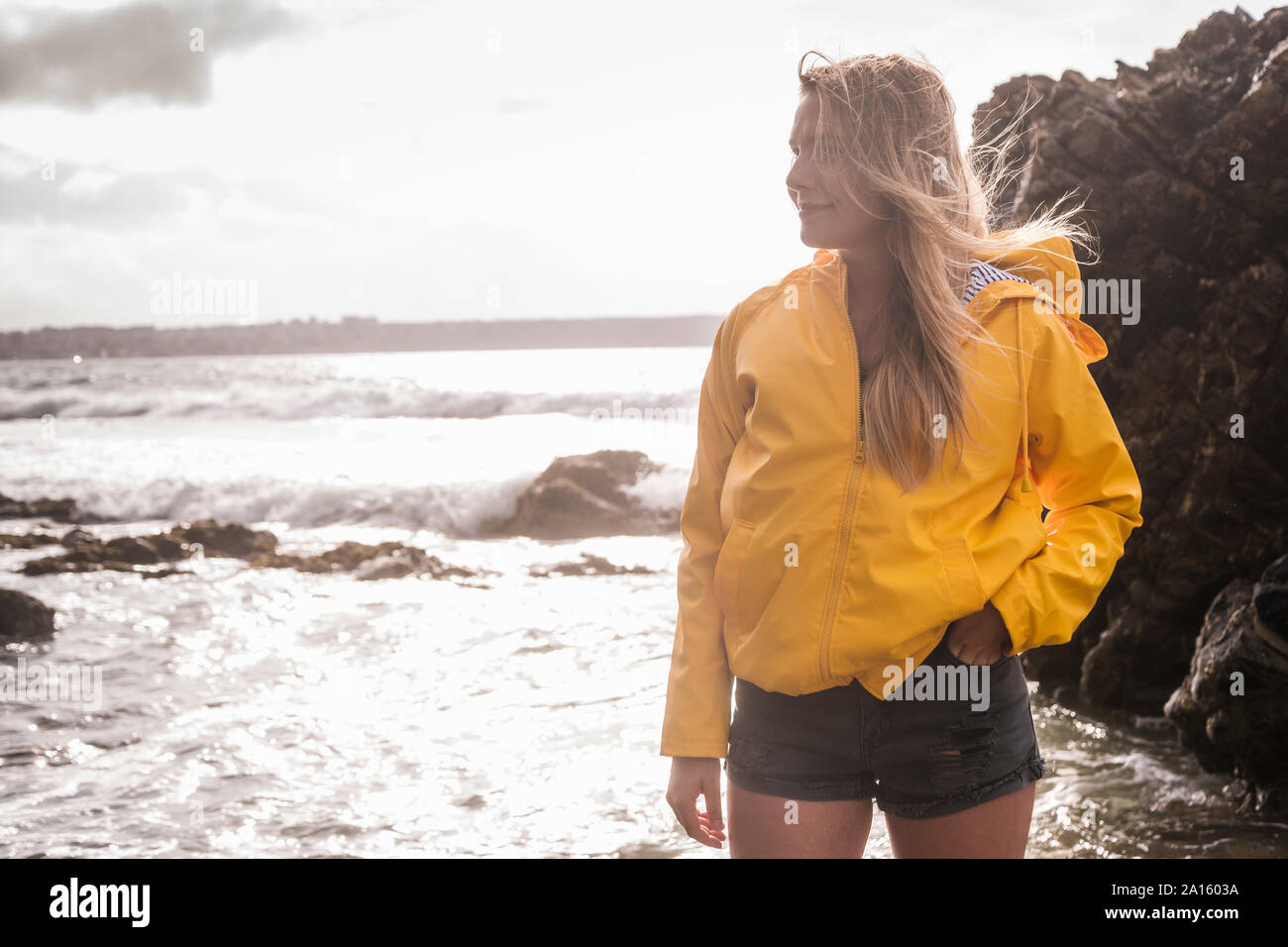 Woman Veste pluie jaune debout à la plage Banque D'Images