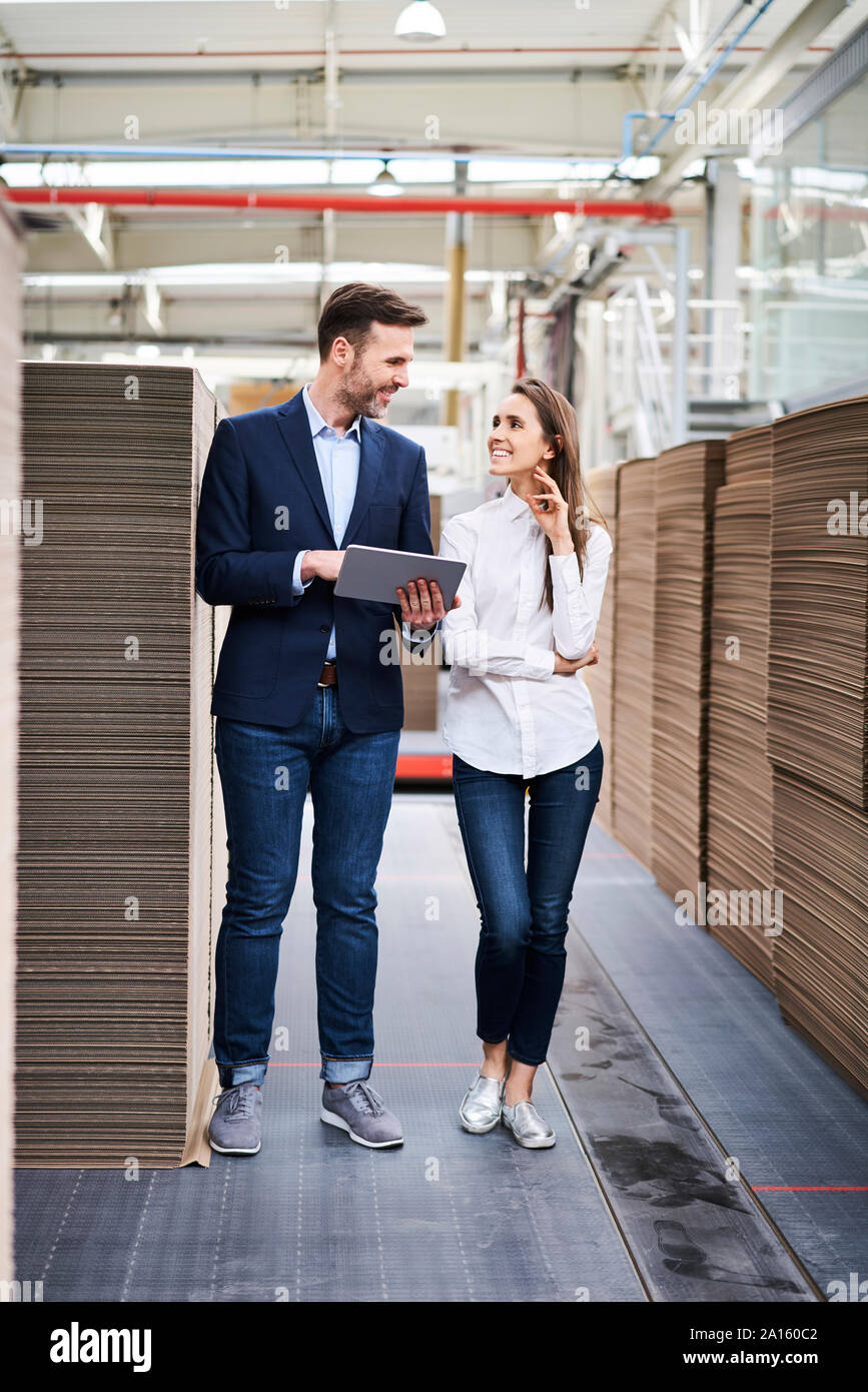 Businessman with tablet and Woman talking in usine-entrepôt Banque D'Images Businessman with tablet and Woman talking in usine-entrepôt Banque D'Images