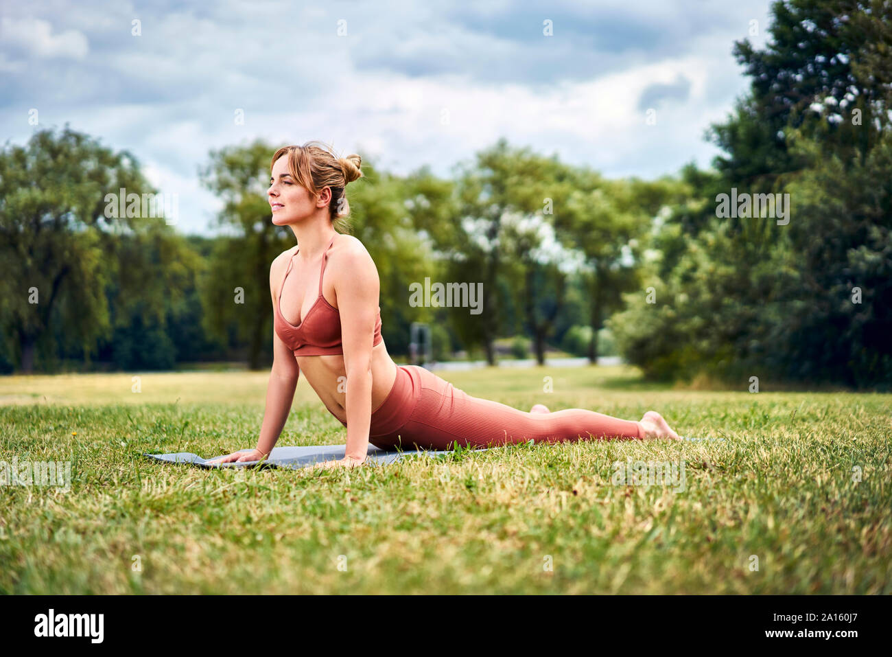 Cobra woman doing yoga pose au cours de la formation dans le parc Banque D'Images