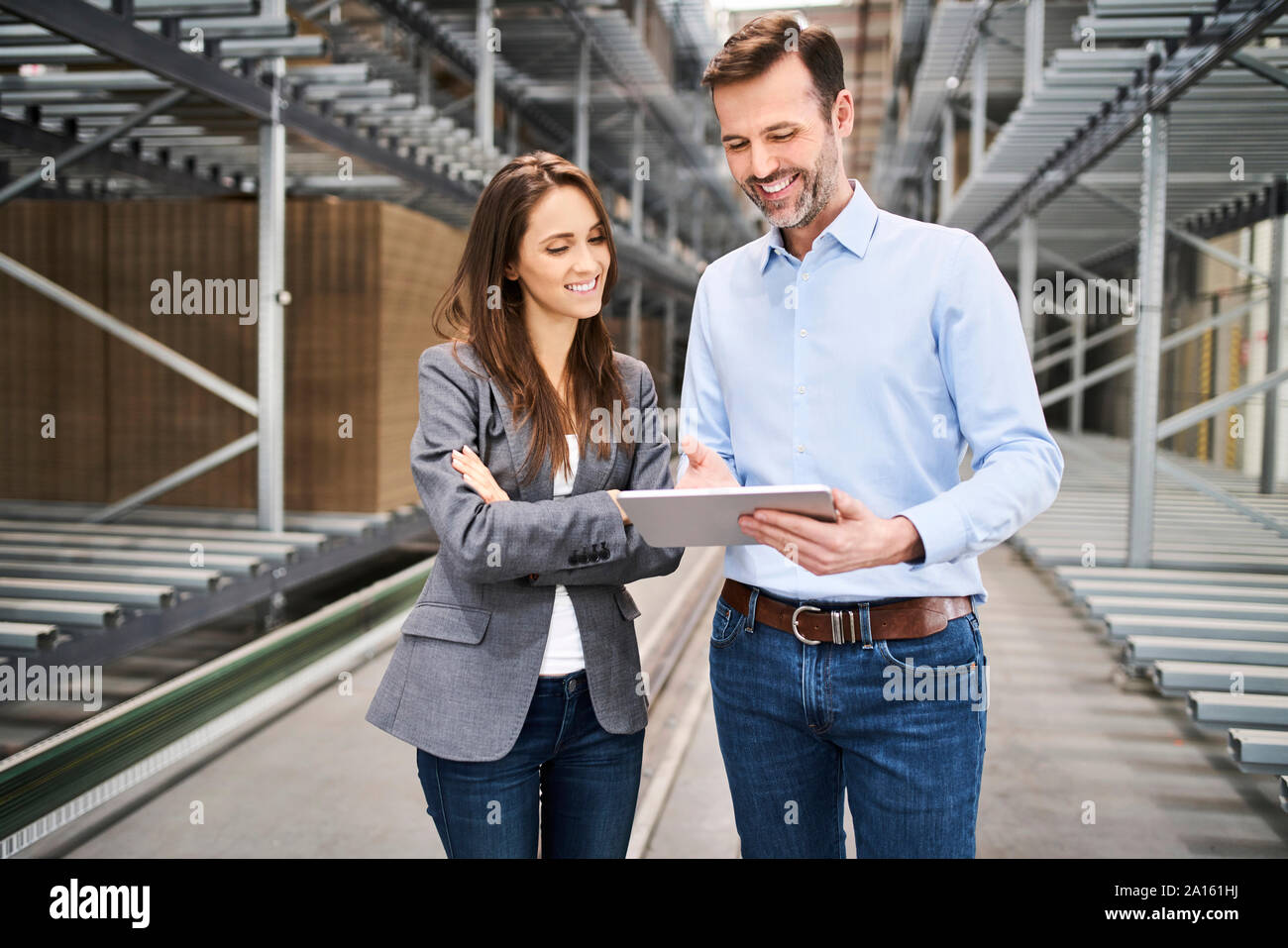 Smiling businesswoman and businessman using tablet dans une usine Banque D'Images Smiling businesswoman and businessman using tablet dans une usine Banque D'Images