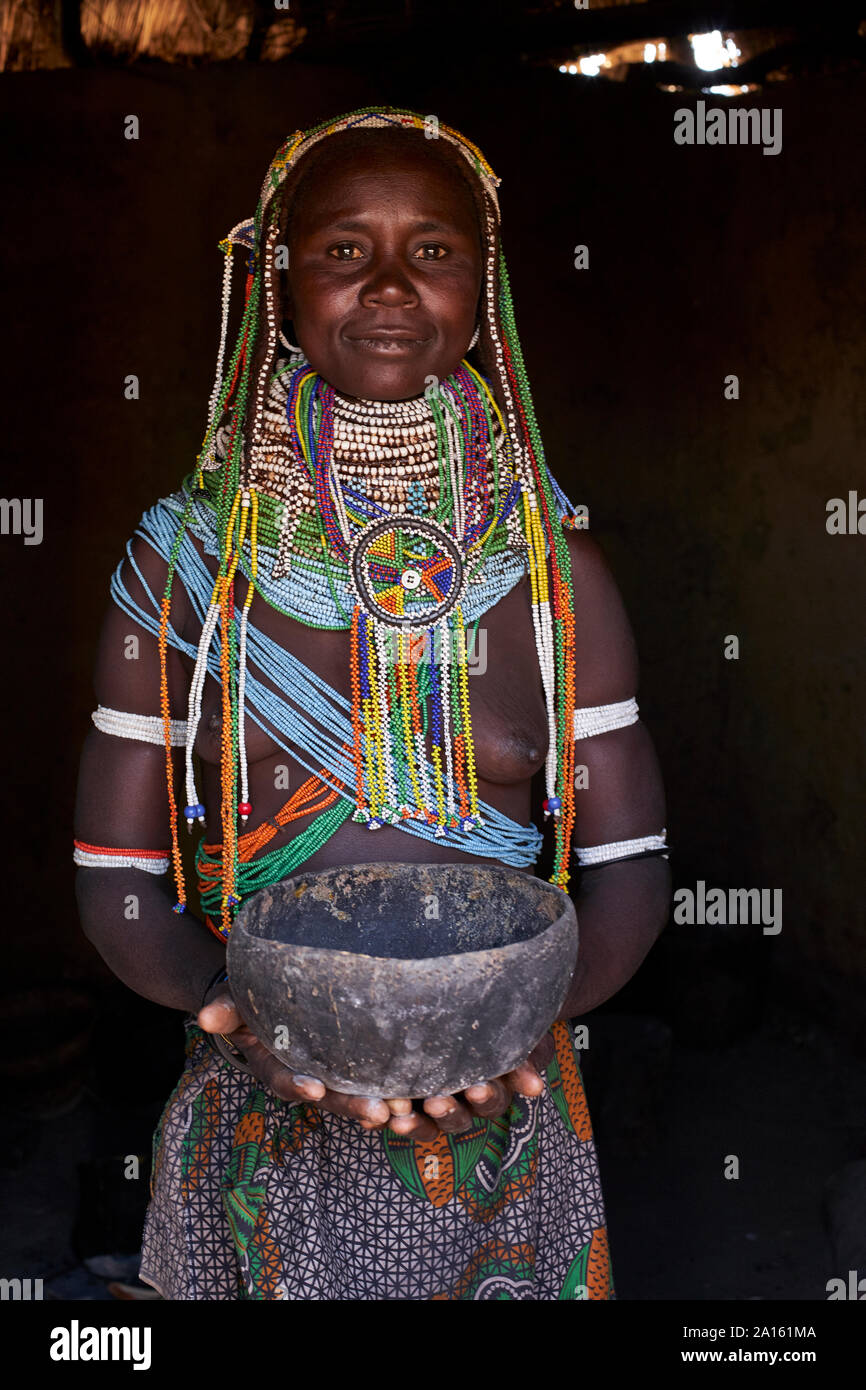 Portrait d'une femme traditionnelle Muhila debout dans sa maison, holding pot, Congolo, Angola Banque D'Images