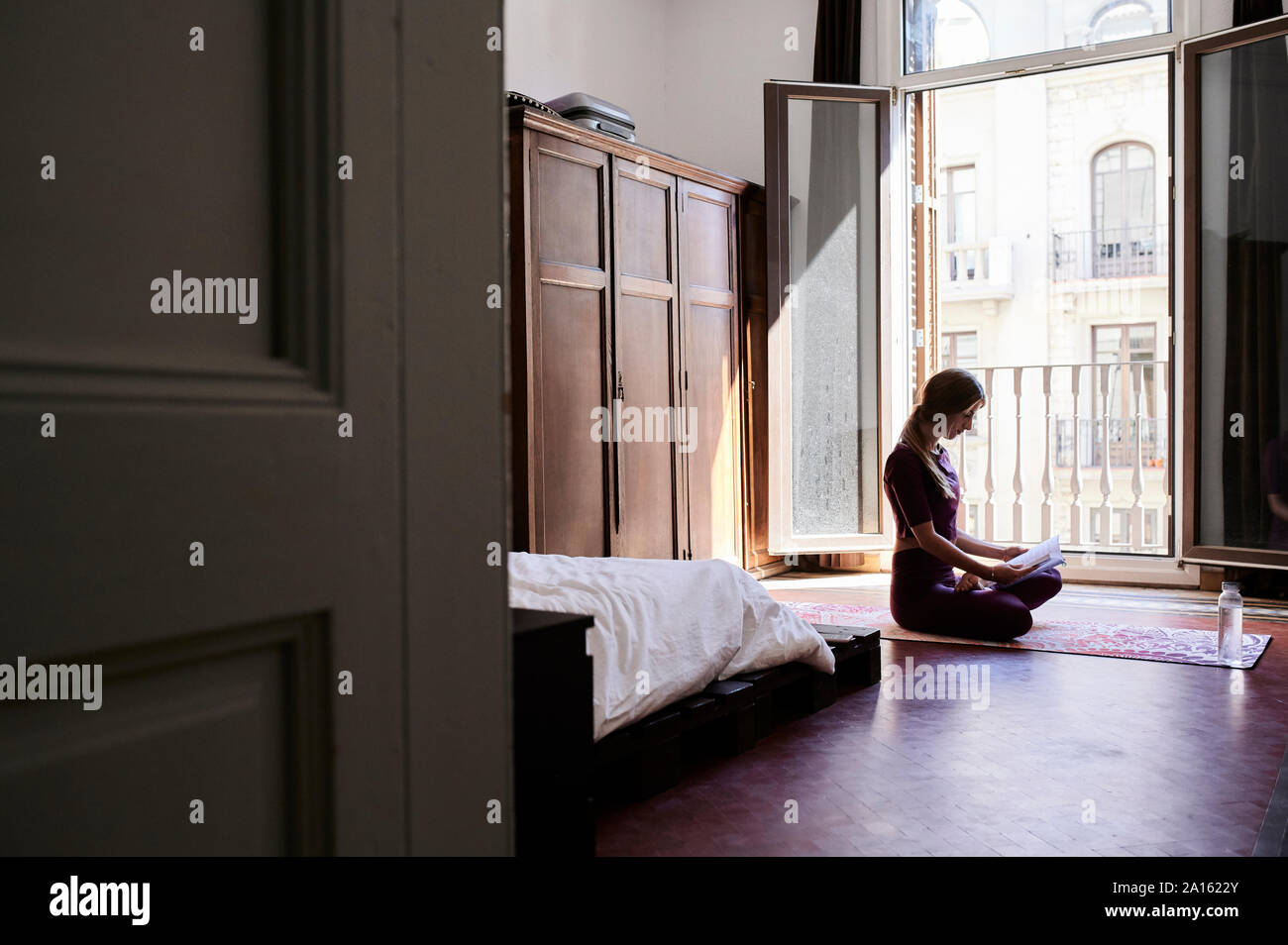 Jeune brunette woman practicing yoga in chambres d'étudiants, la lecture d'un livre Banque D'Images