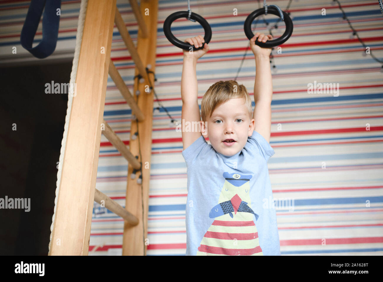 Portrait d'un garçon suspendu à des anneaux de gymnastique Banque D'Images