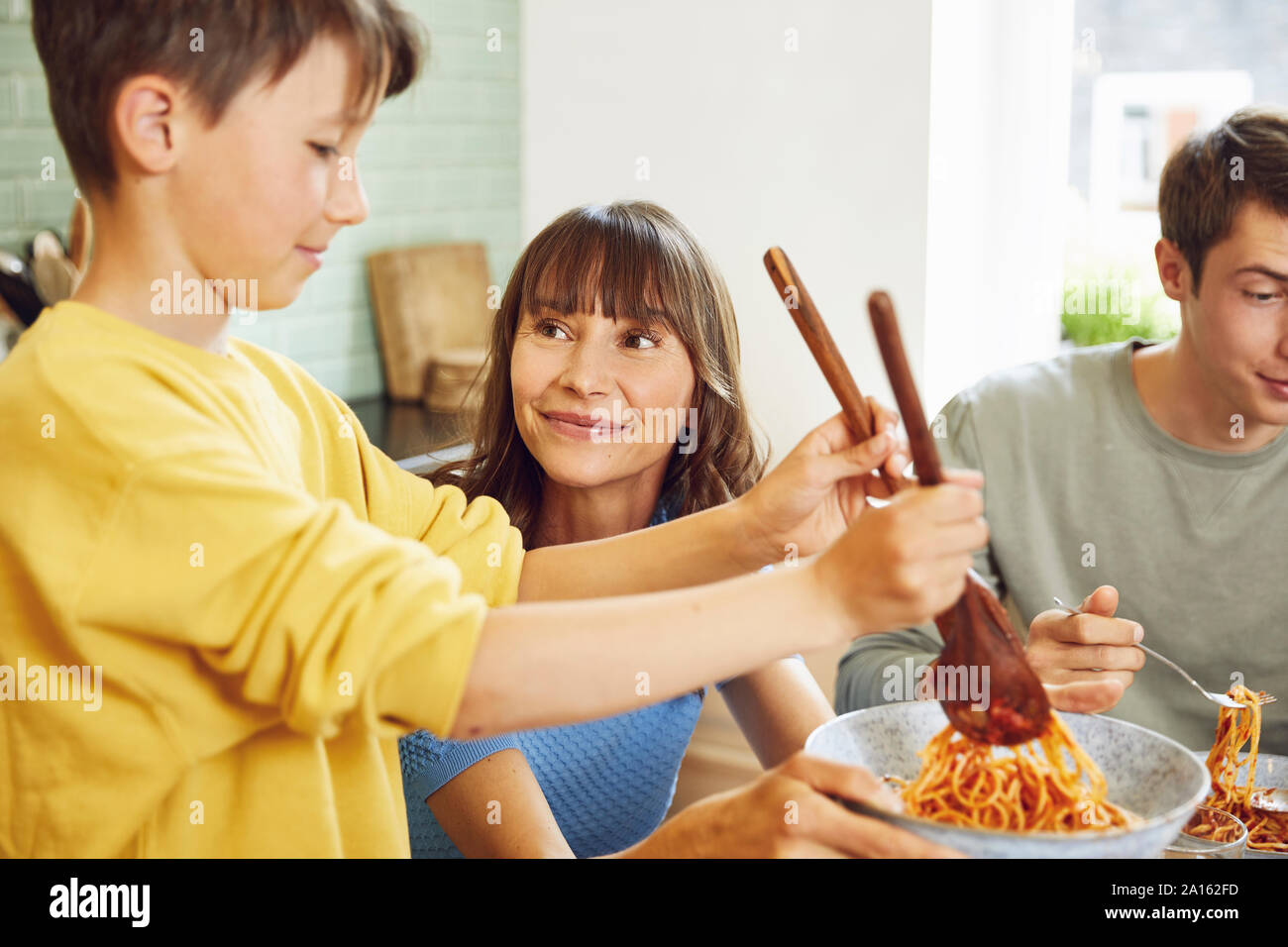 Mère mange du spaghetti avec ses fils dans la cuisine Banque D'Images