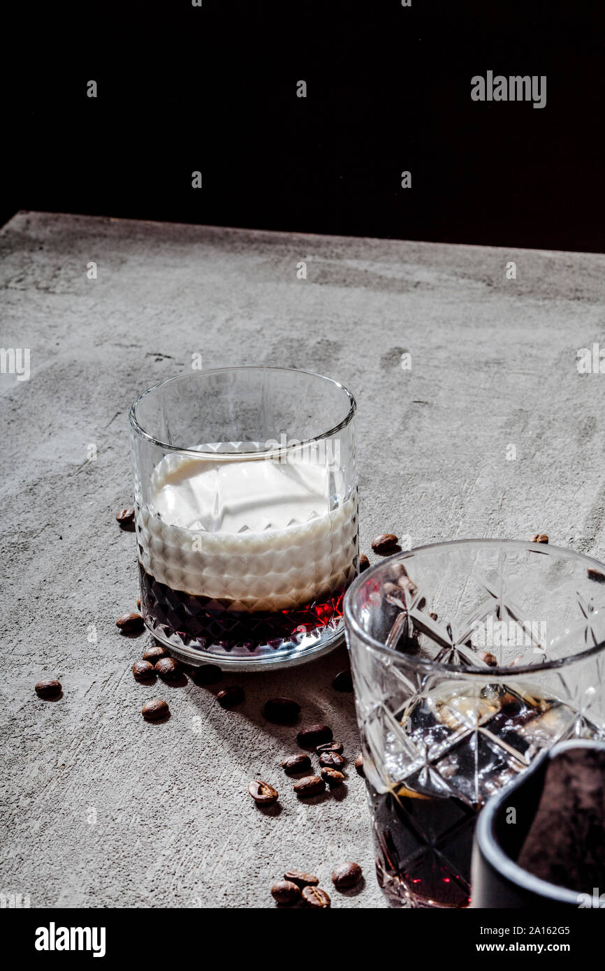 High angle view of White Russian en verre avec des grains de café torréfiés sur table béton Banque D'Images