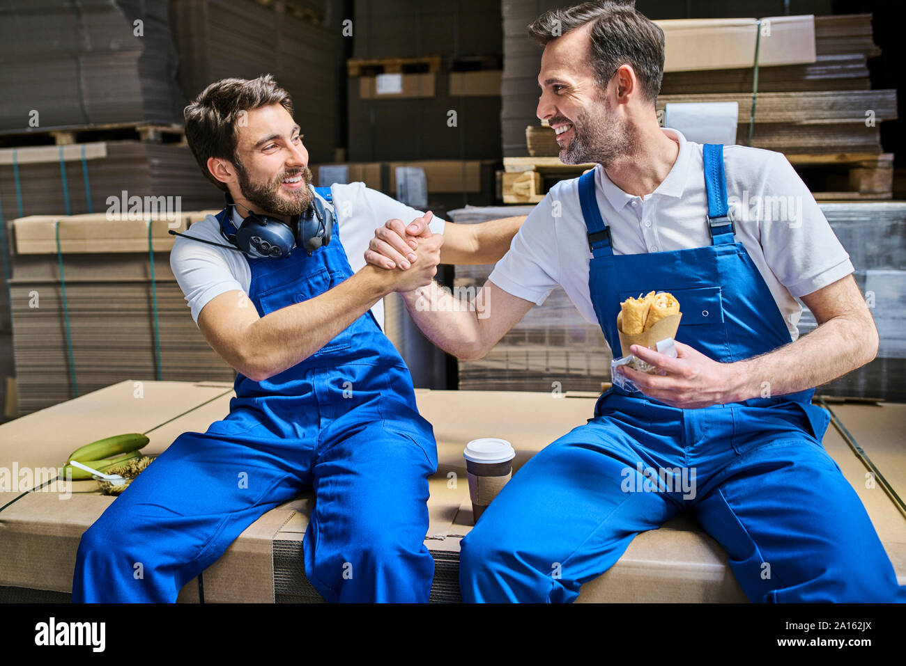 Deux travailleurs heureux avoir pause déjeuner en usine Banque D'Images