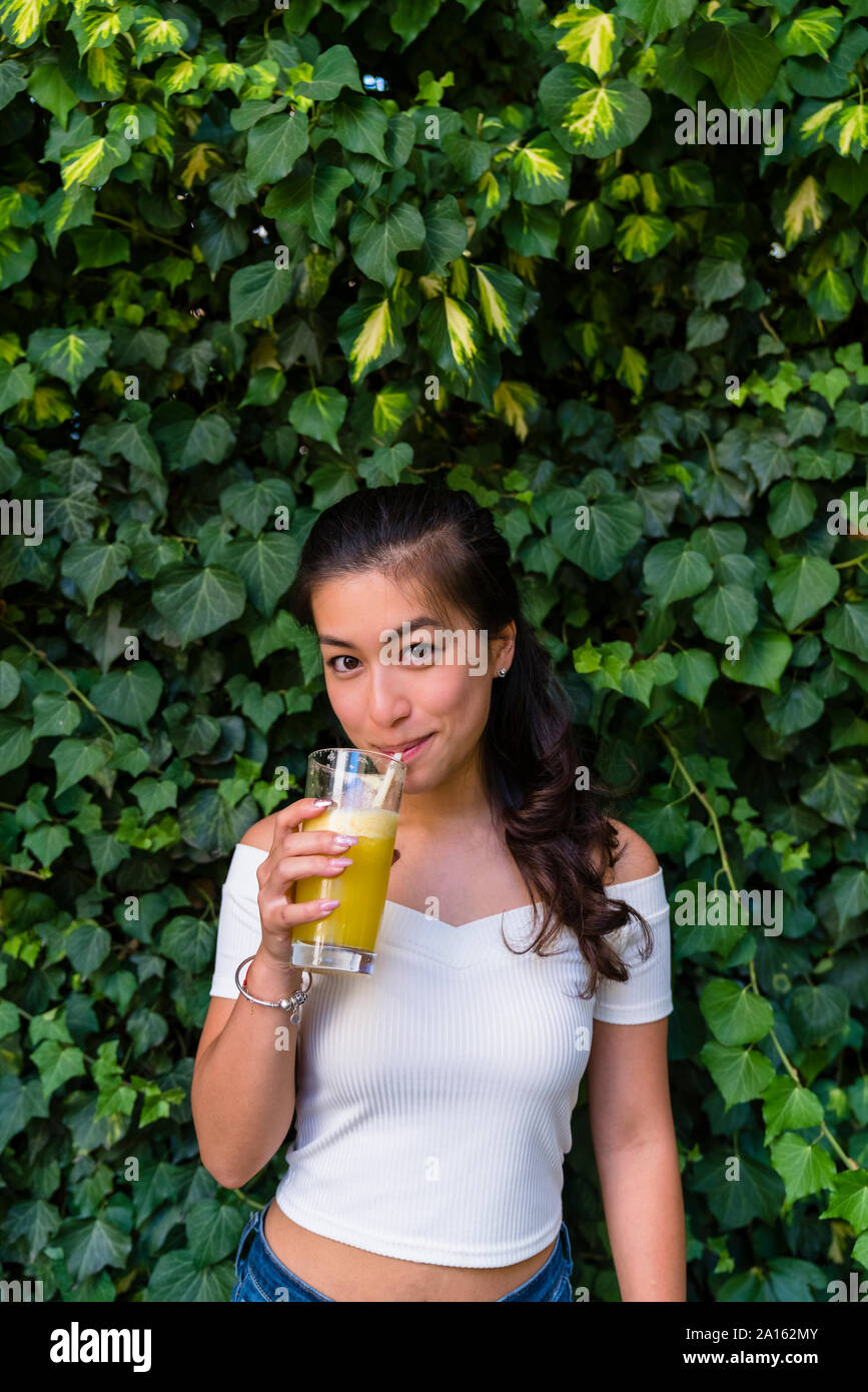 Portrait of smiling young woman drinking une boisson saine Banque D'Images