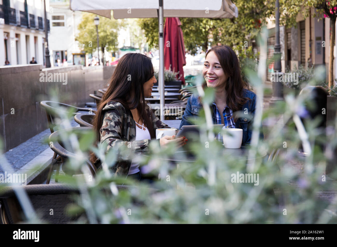 Heureux les jeunes femmes assis dans le café café à l'extérieur ensemble à Madrid, Espagne Banque D'Images
