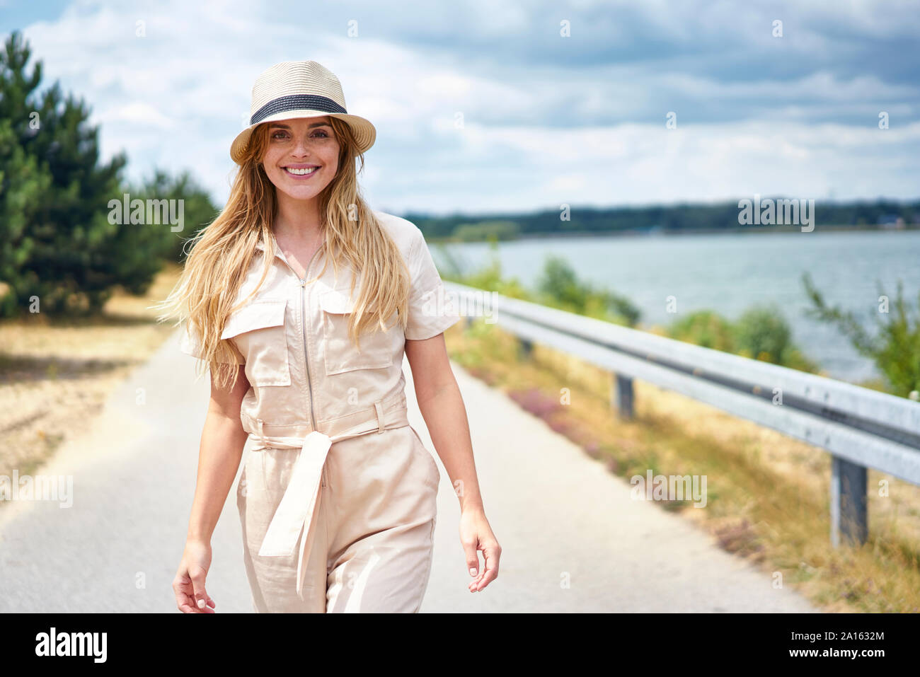 Portrait of smiling woman walking on rural road au bord de lac Banque D'Images Portrait of smiling woman walking on rural road au bord de lac Banque D'Images