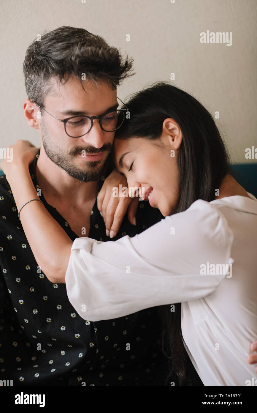 Jeune couple amoureux câlins sur un canapé Banque D'Images