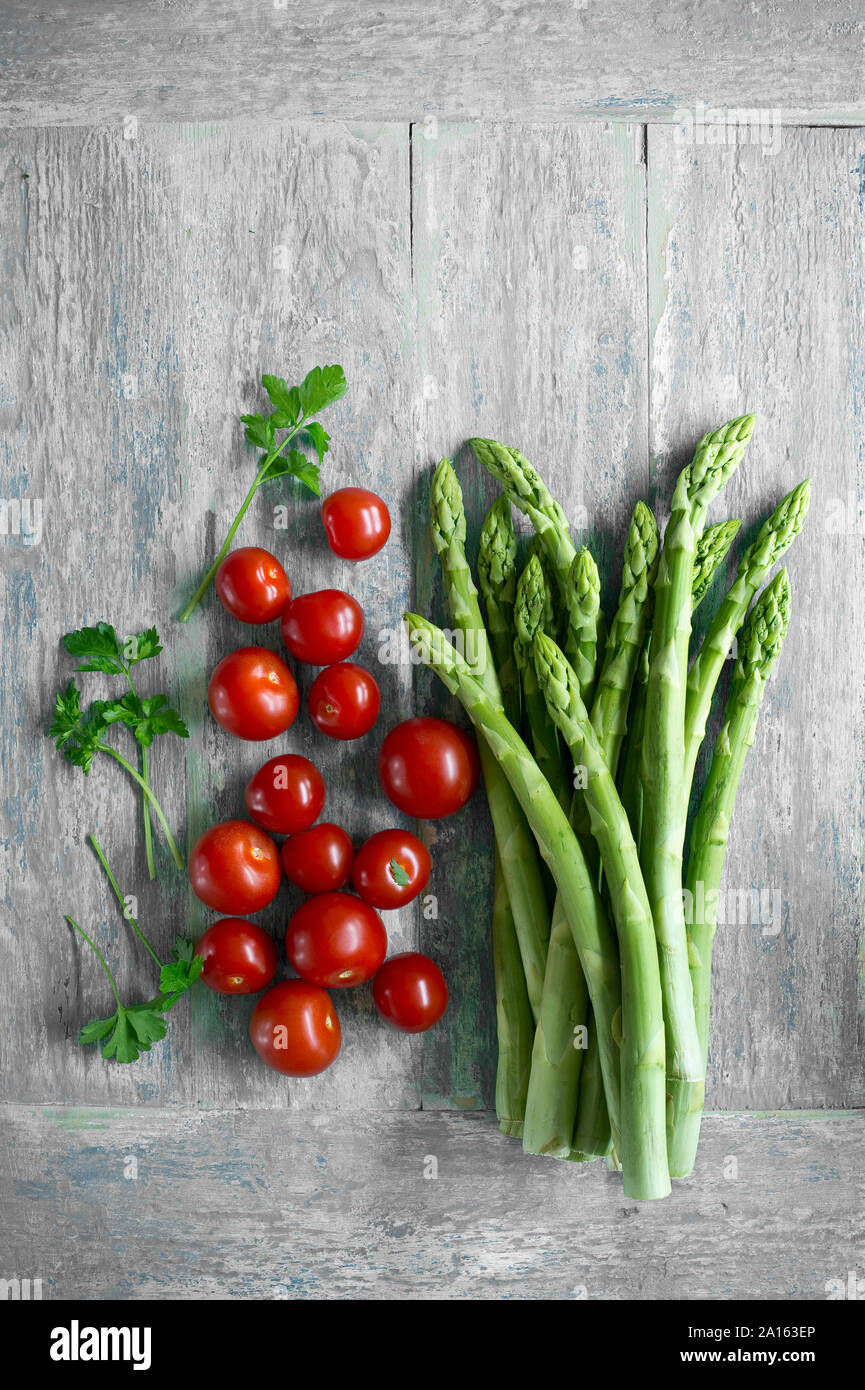 Les asperges vertes, les feuilles de persil et de tomates cerises sur vu de dessus de table en bois Banque D'Images